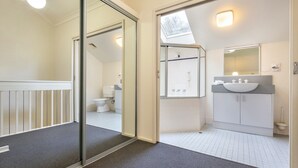 Une salle de bain moderne avec une porte d’entrée en verre, un espace douche et un lavabo surmonté d’un miroir.