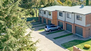 Un bâtiment à deux étages avec un garage, une voiture garée et une pelouse bien entretenue.