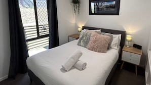 Un lit bien fait, avec une serviette pliée, un tableau encadré accroché au mur et deux tables de chevet avec des lampes.