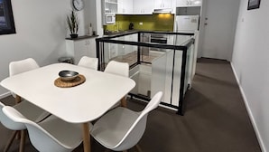 Une cuisine de taille réduite avec des meubles blancs, un four à micro-ondes et un réfrigérateur.