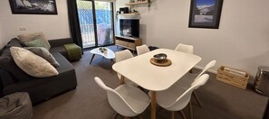 Relax in this inviting space with a comfortable sofa, dining table, and TV, plus a sliding door to an outdoor area.