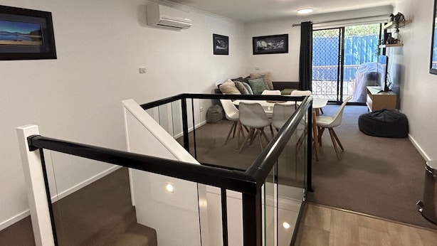 Un intérieur moderne avec un escalier, un coin repas et un balcon offrant une vue.
