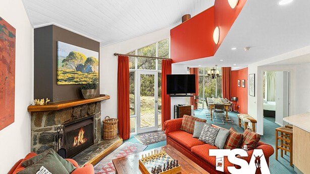 Una sala de estar amplia con chimenea, televisor grande y comedor con vista al exterior.
