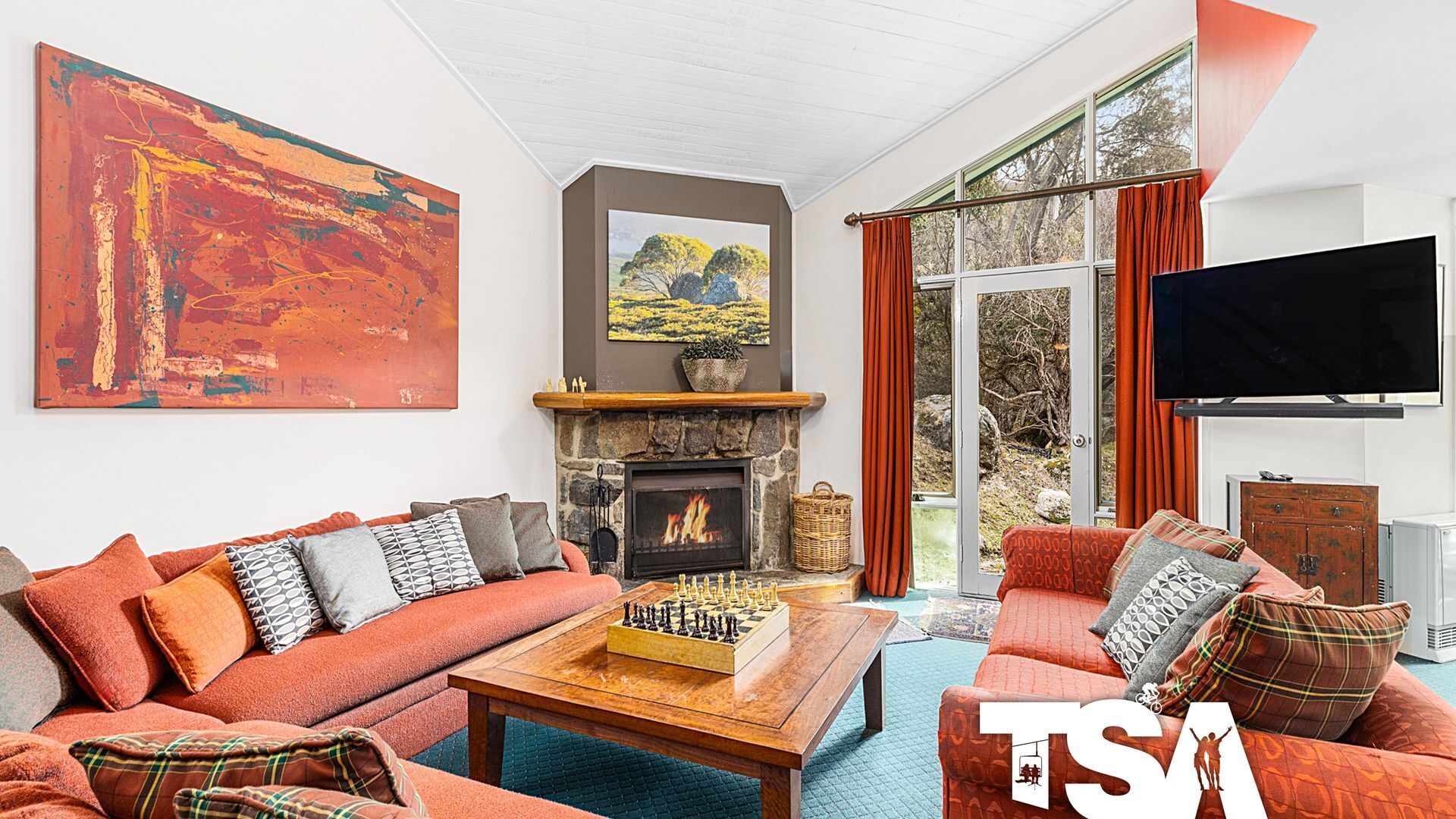 A cozy living room with a fireplace, a large abstract painting, and a television.