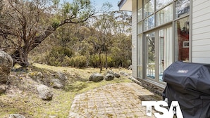 Una casa con un sendero de piedra que lleva a una puerta de cristal, rodeada de árboles y rocas.