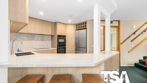 Una cocina moderna con una isla central, horno empotrado y electrodomésticos de acero inoxidable.