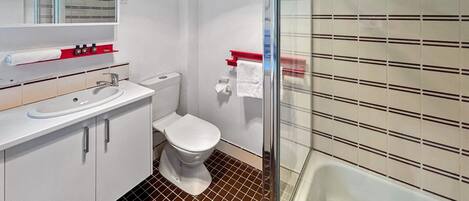 A modern bathroom with a white sink, toilet, and shower. There are toiletries on the sink and a towel rack above the toilet.