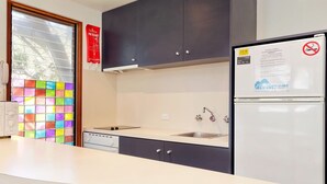 Eine moderne Küche mit Mikrowelle, Kühlschrank und farbenfroher Aussicht aus dem Fenster.
