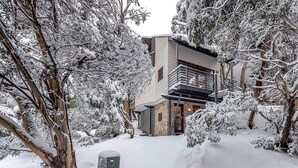 Ein modernes Gebäude mit einem Balkon, umgeben von schneebedeckten Bäumen.