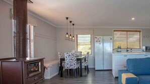 Un espacio habitable compacto con comedor, kitchenette y un sofá azul.