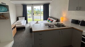 Ein kompaktes Hotelzimmer mit Bett, einer kleinen Küchenzeile, einem Essbereich und Blick ins Freie.