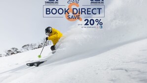 Ein Skifahrer mit gelber Jacke fährt einen verschneiten Hang hinab.