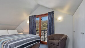 A bedroom with a bed, a nightstand, a chair, and a window with curtains.
