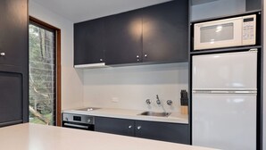 A modern kitchen with dark cabinets, a white countertop, a built-in microwave, and a refrigerator.