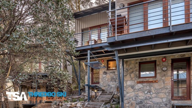 A two-story stone building with a balcony, stone steps leading to the entrance, and a sign reading "Mosswood."
