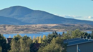 A mountainous landscape with a body of water in the foreground and a building with a dark roof in the foreground.