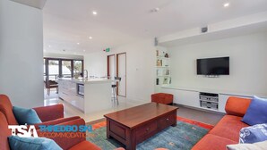 Un espace de vie moderne comprenant un canapé, une table basse et un téléviseur à écran plat fixé au mur.