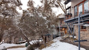 Un bâtiment en pierre doté d’un balcon, entouré d’arbres et de neige.