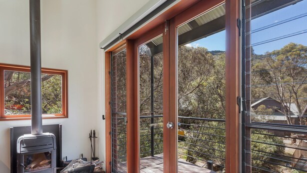 Un balcon donnant sur un paysage rural, avec une balustrade en métal et une porte en bois.