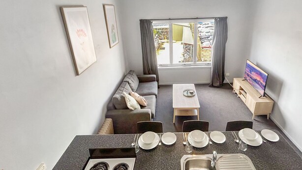 A compact living space with a kitchenette, dining area, and a sofa. - Razorback 14 - Centrally located, lovely 1 bedroom (Jindabyne)