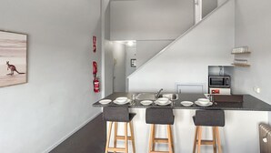 A modern kitchen with a central island, bar stools, a microwave, and a fire extinguisher. - Razorback 14 - Centrally located, lovely 1 bedroom (Jindabyne)
