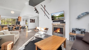 A modern living room with a fireplace, dining area, and kitchen.