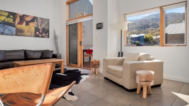 A modern living room with a sofa, a chair, a coffee table, and a view of the outdoors.