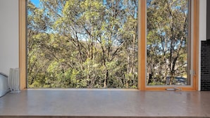 A room with a large window overlooking a dense tree area.