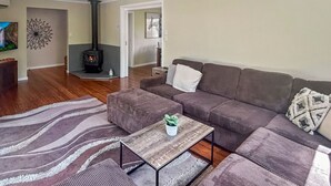 Ett vardagsrum med en soffa, ett soffbord, en öppen spis, en tv och en matta.