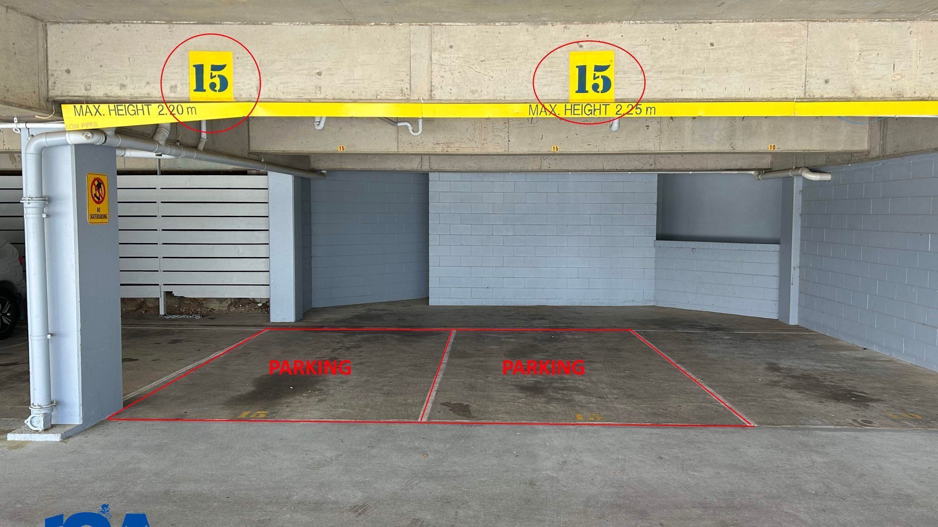 A parking garage with two marked parking spaces, a height restriction sign, and a no smoking sign.