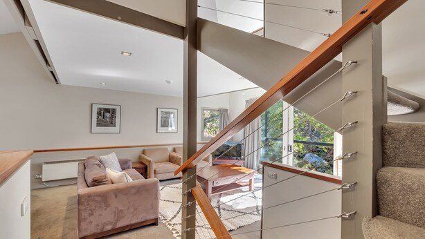 Una sala de estar moderna con una escalera, un sofá y una mesa de centro.