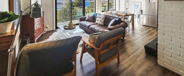 Ein gemütliches Wohnzimmer mit einem Ledersofa, einem Holztisch und einem Essbereich mit Tisch und Stühlen.