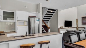 Een moderne keuken met een roestvrijstalen koelkast, een magnetron en een houten kookeiland met krukken.