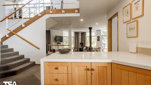 A modern kitchen with a central island, wooden cabinets, and a staircase leading to an upper level. - Rileys Run - Woodridge (Woodridge)