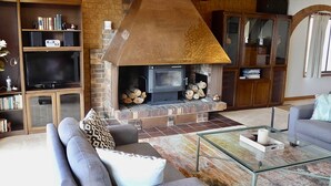 A living room with a fireplace, a sofa, a glass coffee table, and a television.