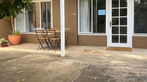 Un espace patio avec une table et des chaises, une plante en pot et une porte avec une pancarte.