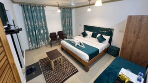 A neatly arranged bedroom with a bed, bedside tables, a desk, and a chair. - HOTEL WEST INN BOULEVARD (Srinagar)