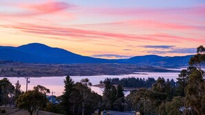 A scenic landscape with a lake, mountains, and trees. - Alpine Mountain View 40 (Jindabyne)