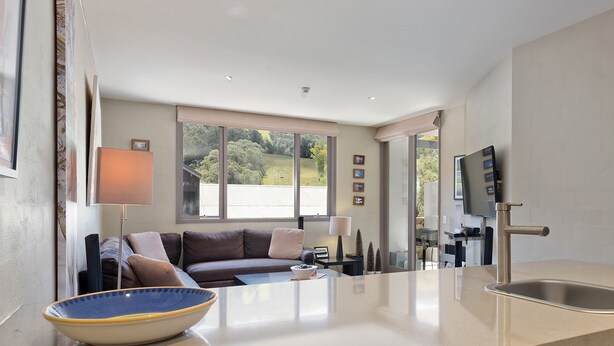 A modern kitchen with a large window, a sofa, and a dining area.