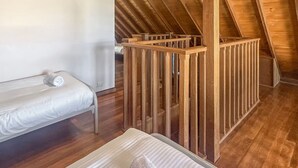 Een knus slaapkamer op zolder met een stapelbed, houten balken en een schuine plafond.