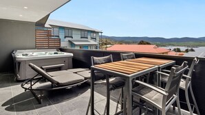 Eine Dachterrasse mit Whirlpool, Sitzgelegenheit und Blick auf ferne Hügel.