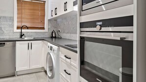 Eine moderne Küche mit weißen Schränken, einem Geschirrspüler von Bosch, einer Waschmaschine von Siemens und einem Backofen von Panasonic.