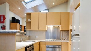 Eine moderne Küche mit Holzausstattung, einem Edelstahlherd und einem eingebauten Backofen.