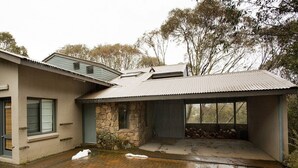 Ein modernes Haus mit Steinuntergrund, großen Fenstern und einem überdachten Veranda-Bereich.