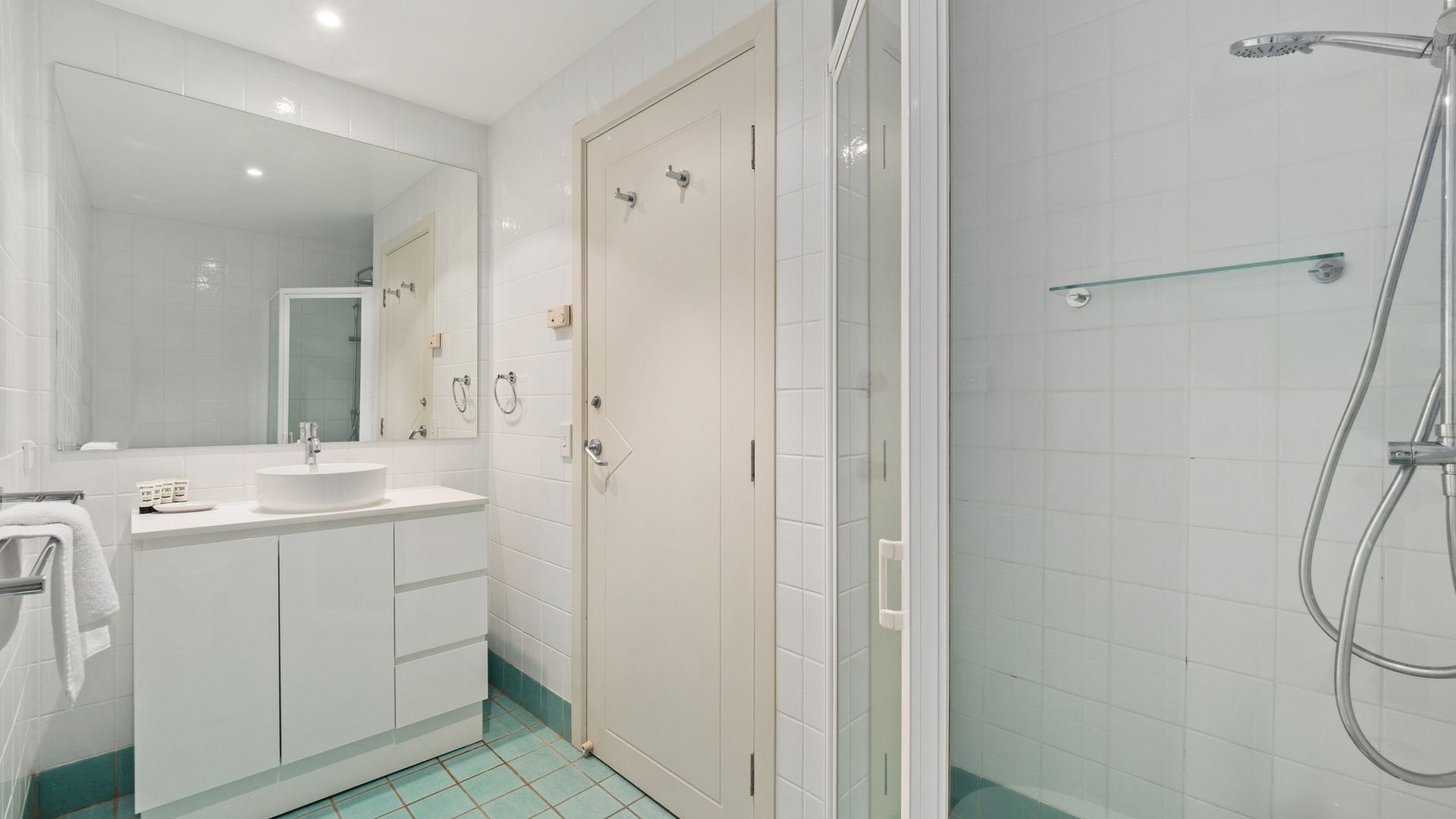 A modern bathroom with a large mirror, a sink, and a shower area.