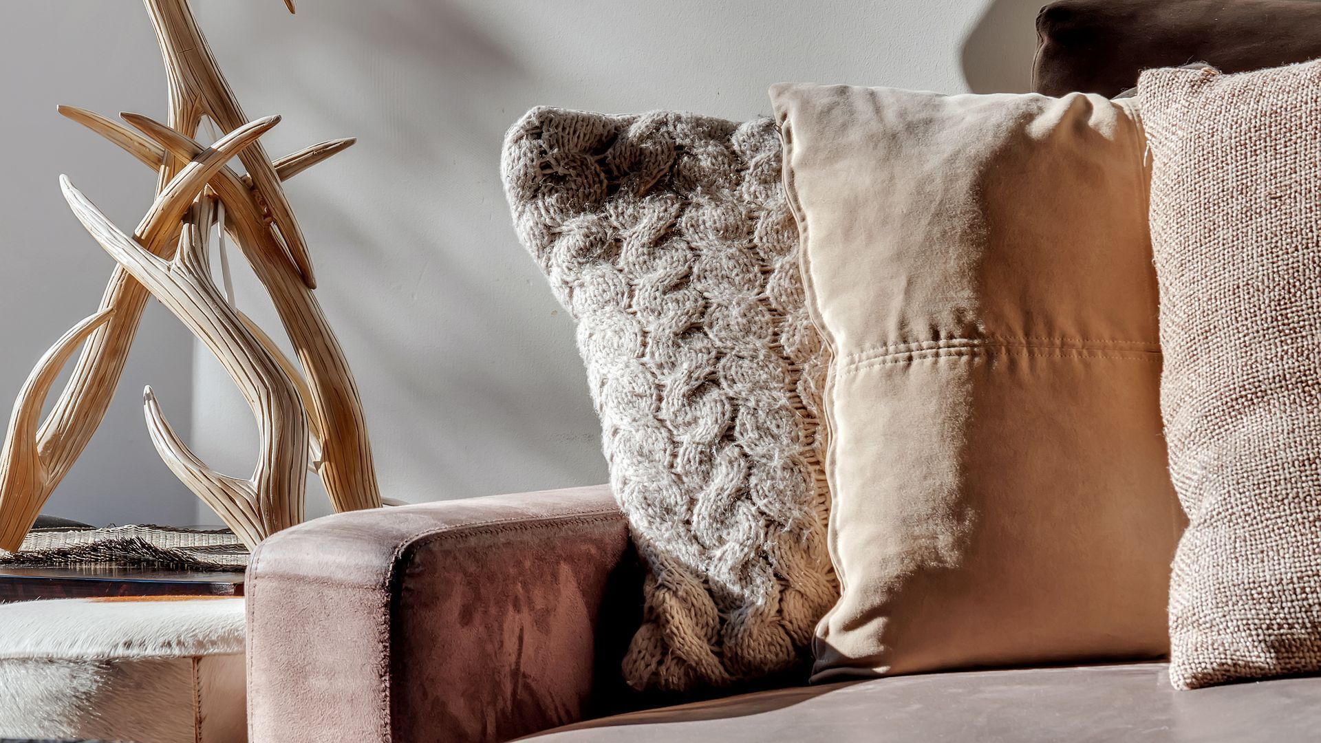 Un canapé moelleux agrémenté d’un coussin texturé et d’un coussin lisse, d’une sculpture décorative en bois et d’un coussin doux et confortable.