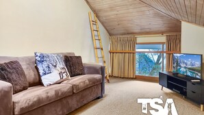 A living room with a sofa, a TV, and a window with curtains.