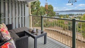 A balcony with a view of a lake and mountains, a glass-top table, and wicker furniture. - Birralee 1 great lake and mountain views (Jindabyne)