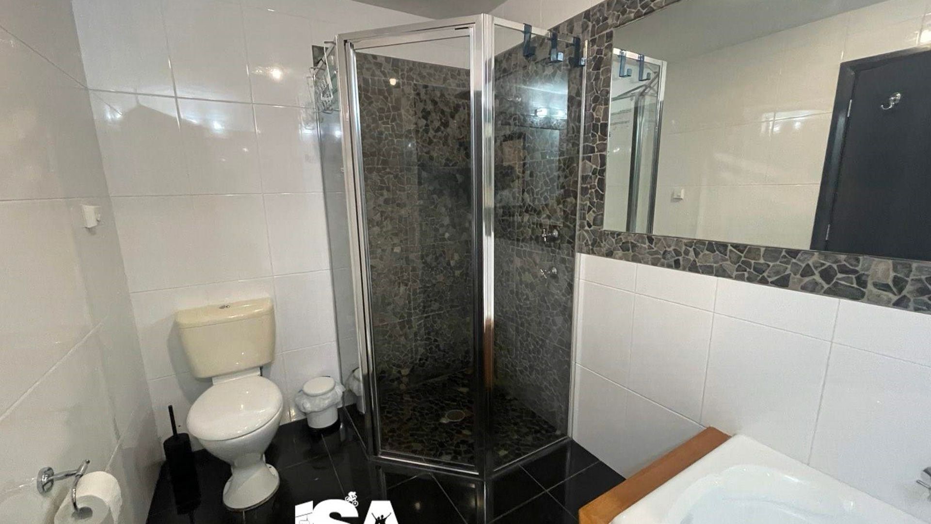 A modern bathroom with a glass-enclosed shower, a toilet, and a bathtub.