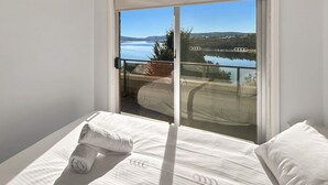 Une chambre avec une grande fenêtre donnant sur un lac et des montagnes.